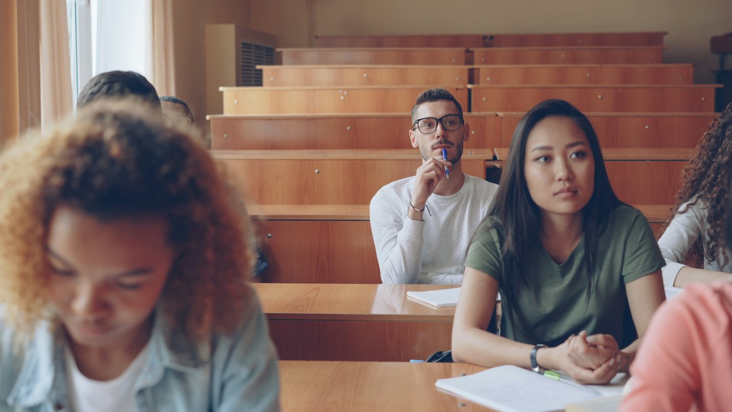Studenci uważnie słuchają wykładu w sali lekcyjnej.
